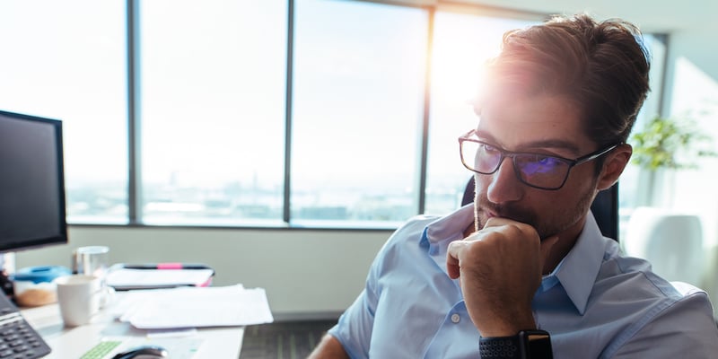 Businessman at a computer considering if his bank can make his loan or if he should consider a hard money loan instead