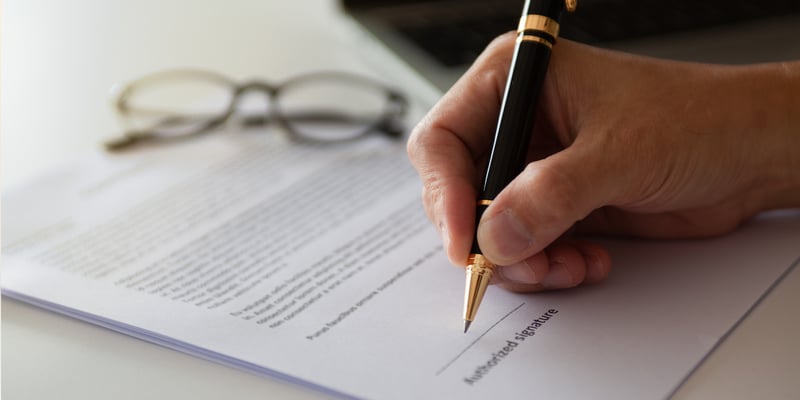 Man reviewing and signing a business partnership buyout agreement contract