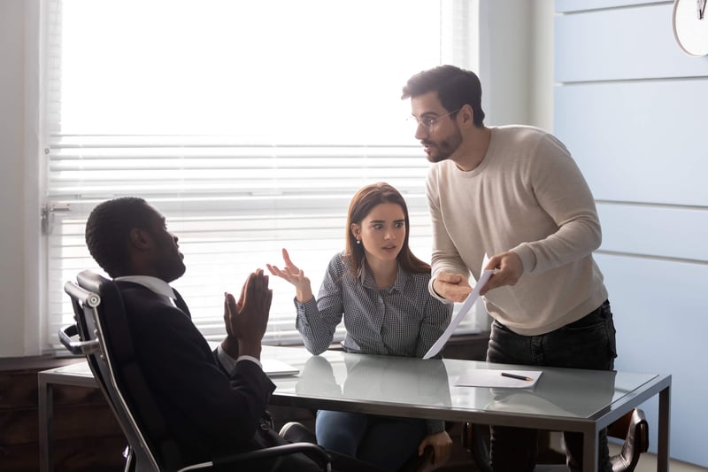 Angry real estate investor yelling at banker pointing to an error on hard money loan document.