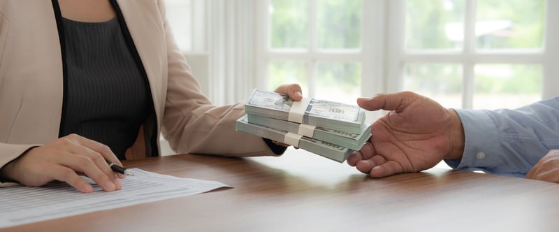 Woman giving money to man who just got a fix-and-flip loan